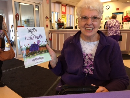 Blog Photo - BOAA - Lady holds Myrtle Book and smiles